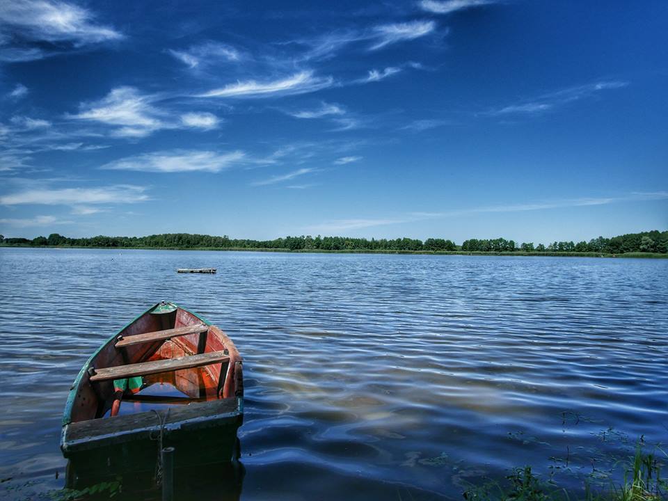Zdjęcie przedstawiające jezioro i łódkę 