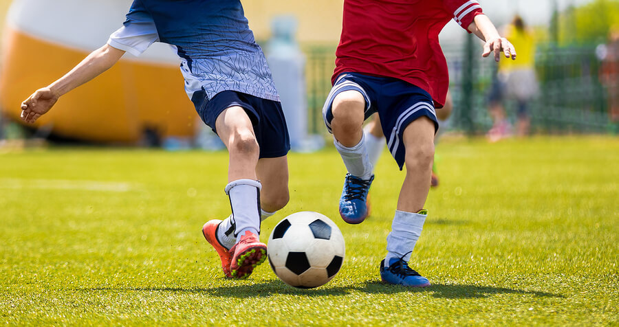 Zdjęcie przedstawia dwóch chłopców grających w piłkę nożną