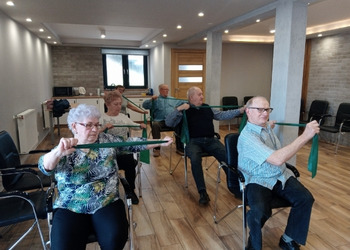 Zdjęcie przedstawia uczestników Klubu Seniora podczas zajęć z gimnastyki ogólnorozwojowej