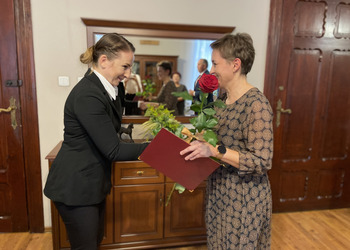 Zdjęcie przedstawia Sekretarz Gminy i Nauczycielkę wręczając różę