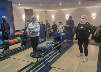 na zdjęciu seniorzy grają w kręgle 