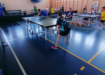 zdjęcie przedstawia uczestników biąrcych udział w turnieju tenisa stołowego podczas rozgrywek
