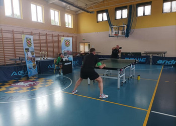 zdjęcie przedstawia uczestników biąrcych udział w turnieju tenisa stołowego podczas rozgrywek