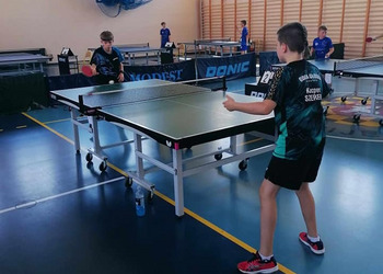 zdjęcie przedstawia uczestników biąrcych udział w turnieju tenisa stołowego podczas rozgrywek